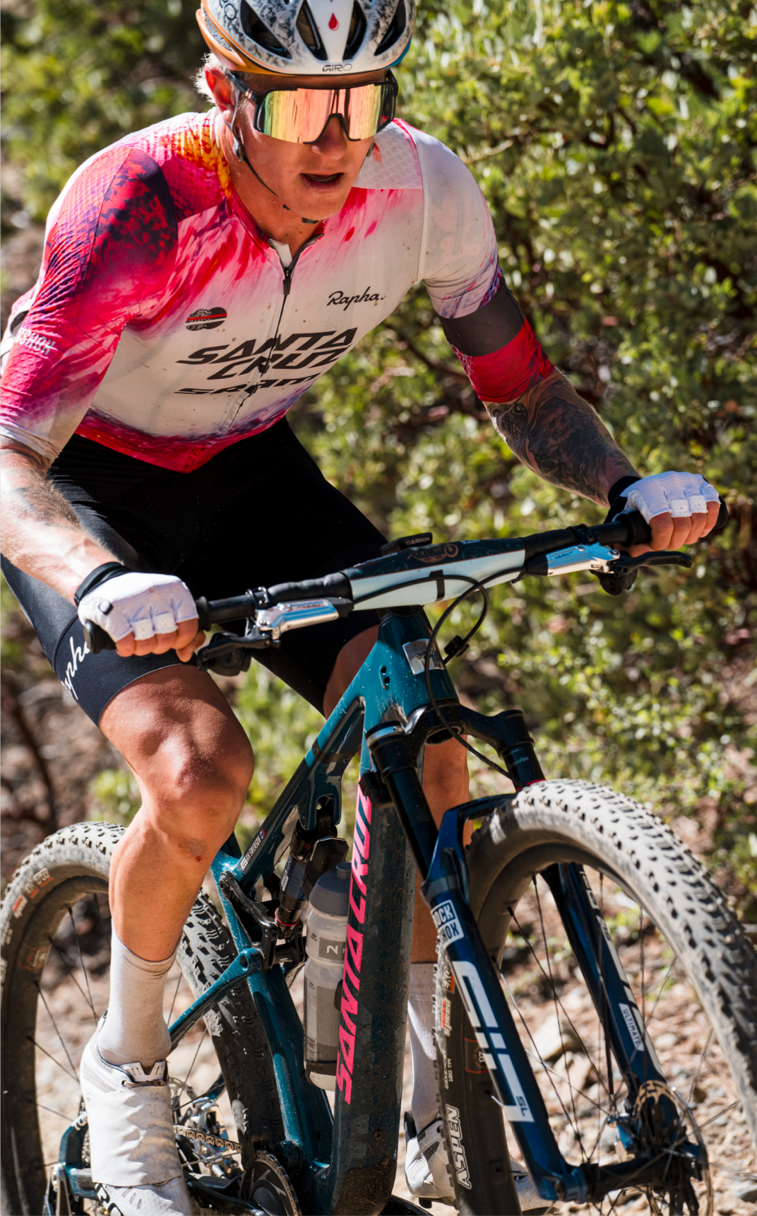 Focused cyclist riding a Santa Cruz mountain bike on a rugged trail, wearing a vibrant jersey and helmet