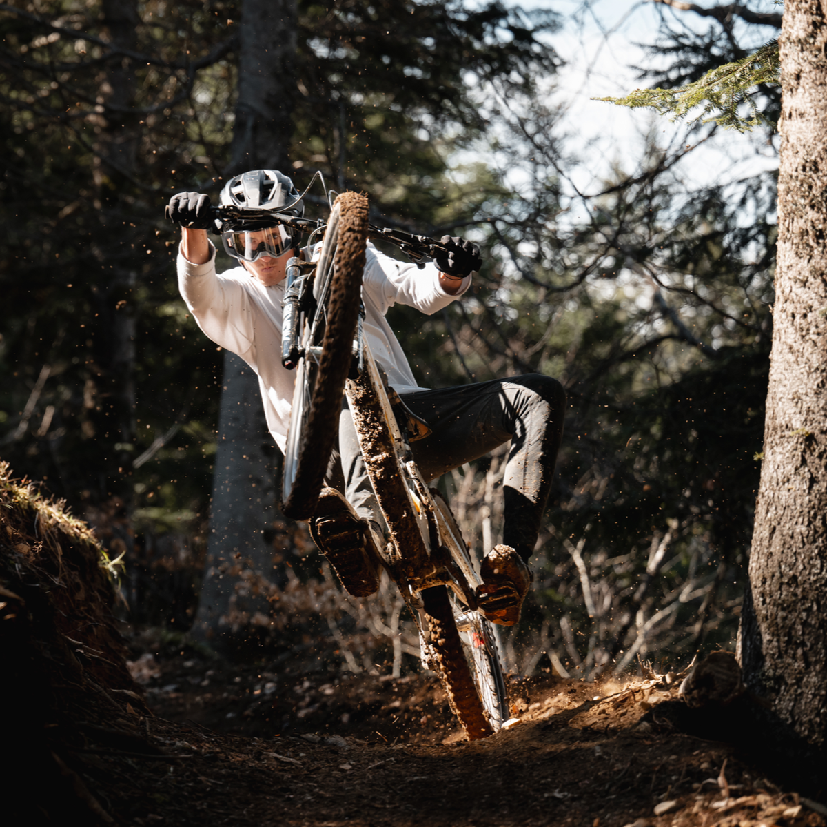 A rider manualing out of a corner on a loamy trail in the forest.