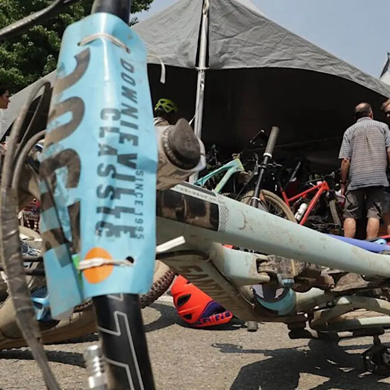 A close-up of a bike at the Downieville Classic event, with tents and bikes visible in the background