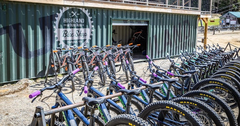 Highland Mountain Bike Park bike shop, showcasing rows of mountain bikes in a rugged outdoor setting