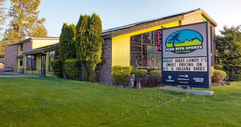 Pine Mountain Sports storefront in Bend, Oregon, featuring a vibrant yellow facade and a welcoming lawn area