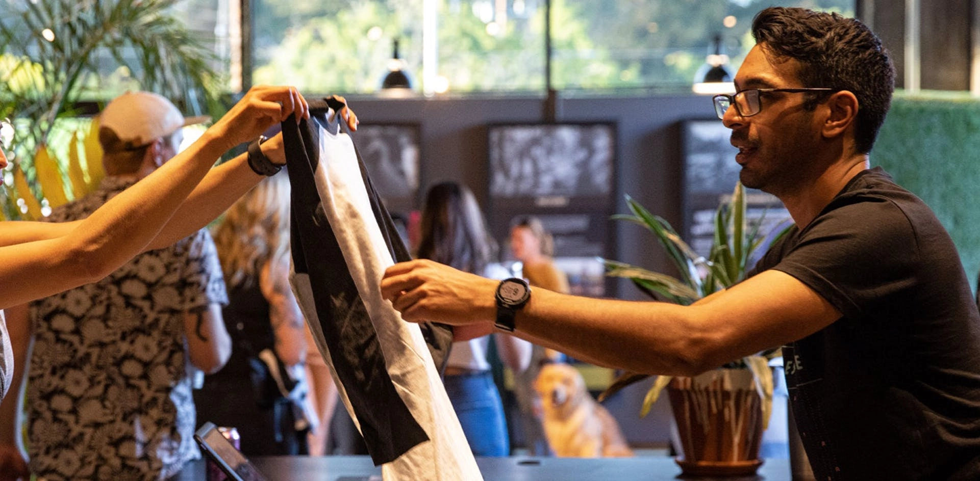 Person handing over a t-shirt at a community event in a warmly lit indoor setting