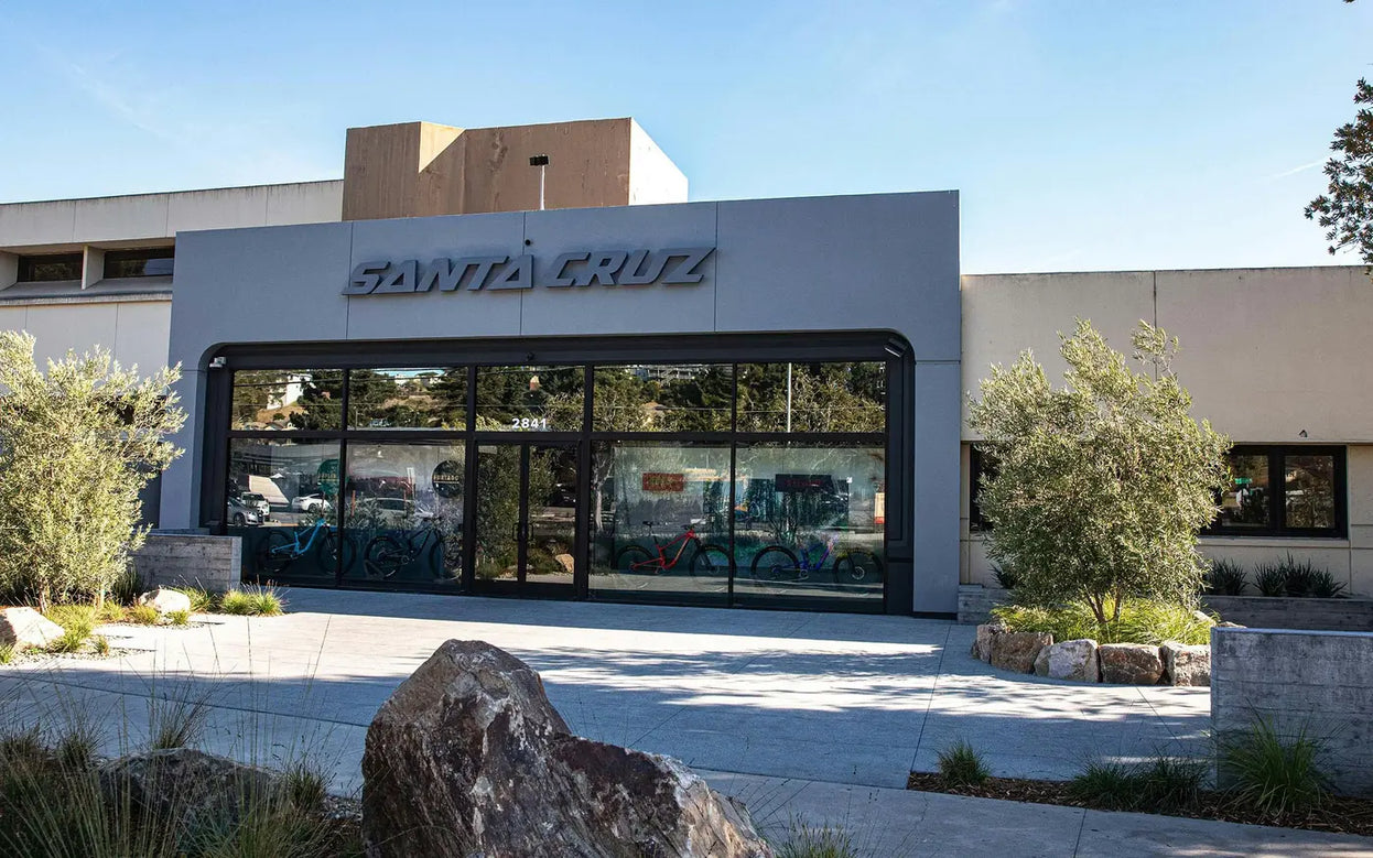 The exterior of the Santa Cruz headquarters, featuring a modern facade with large glass windows displaying bikes, surrounded by neatly landscaped greenery