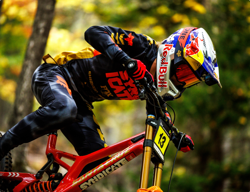 A focused Santa Cruz Syndicate rider leans into the action, showcasing precision and speed on a downhill trail