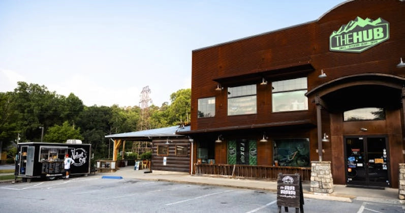 The Hub and Pisgah Tavern, a rustic-style outdoor gear store with a food truck in front, set in lush greenery