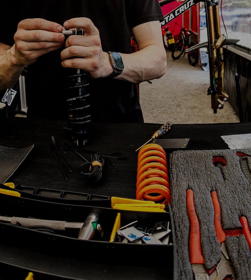 A technician assembles or repairs a bike suspension coil with tools and components neatly arranged on a workstation