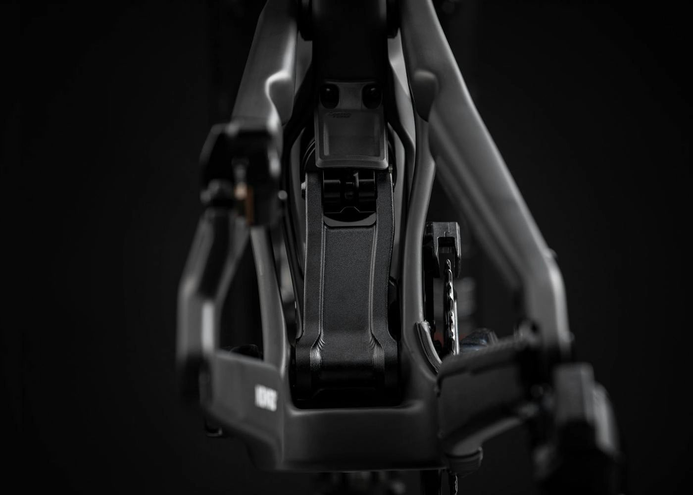 A focused view of a bike's rear triangle and linkage assembly, emphasizing durability and precision, set against a black background